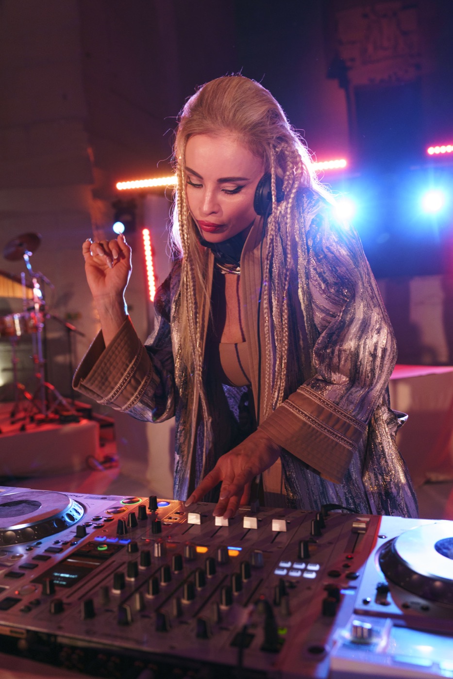 DJette casque sur les oreilles à la table de mixage, lumière rouge, Drop Music