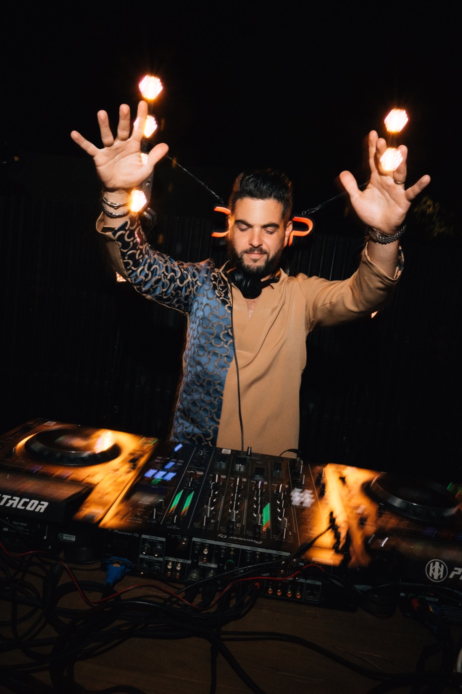 DJ bras levés derrière ses platines, entouré d’ampoules, Drop Music