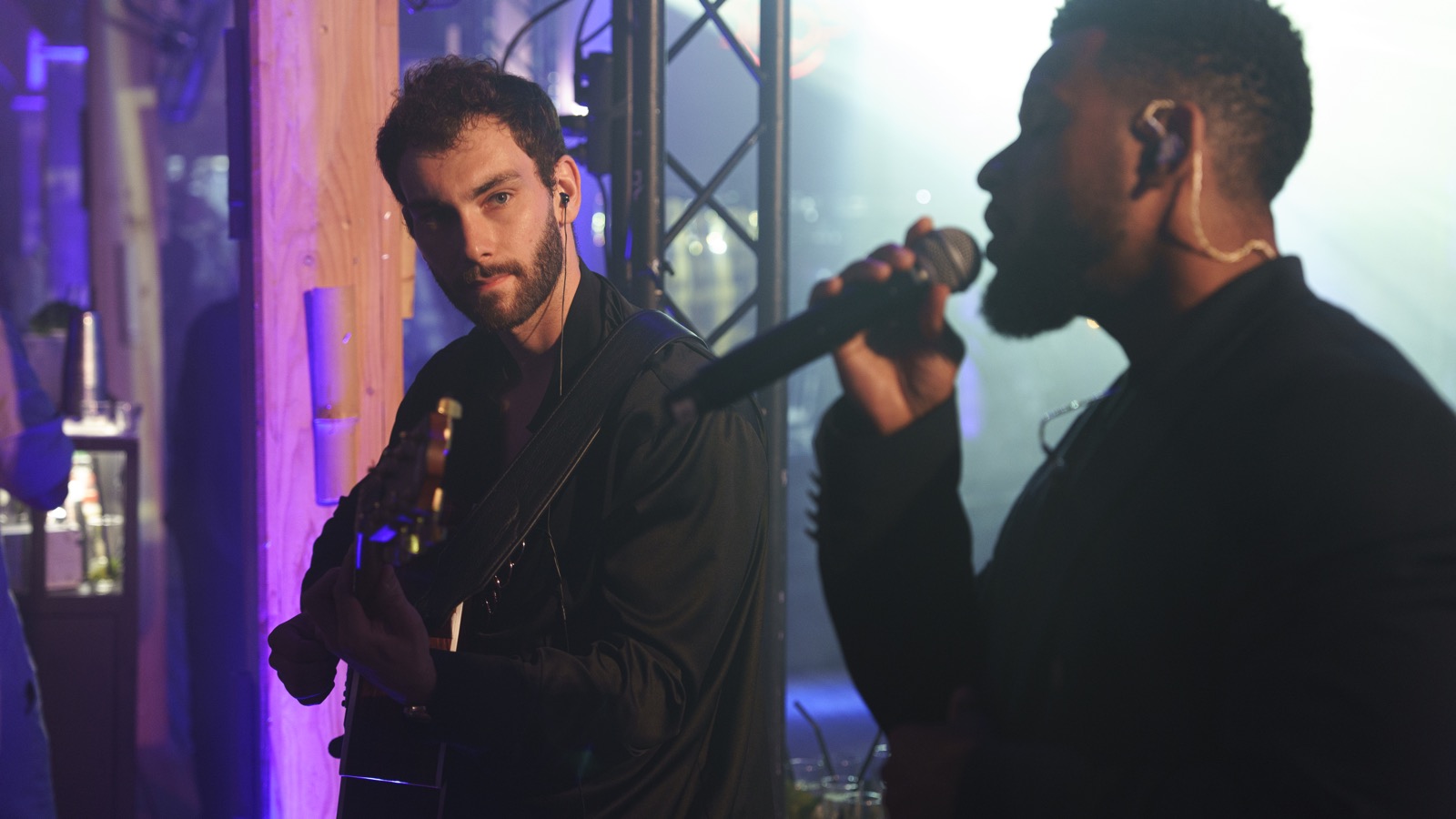 Silhouettes d’un guitariste et d’un chanteur à contre-jour bleu sous un lustre, Drop Music
