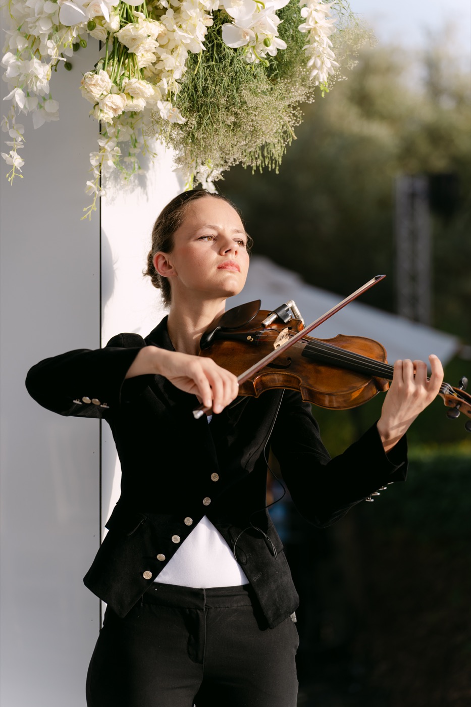 Violoniste en veste noire sous une composition de fleurs blanches, en extérieur, Drop Music