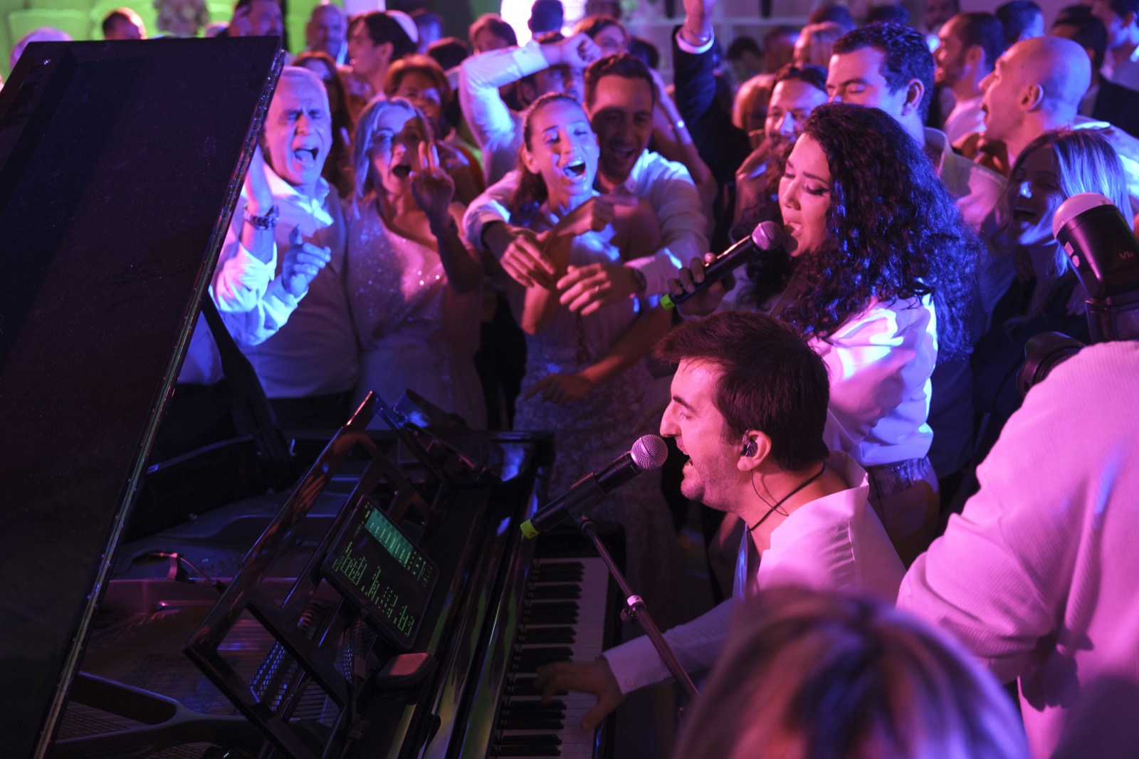 Pianiste qui chante au piano à queue, une chanteuse et les invités serrés autour, Drop Music