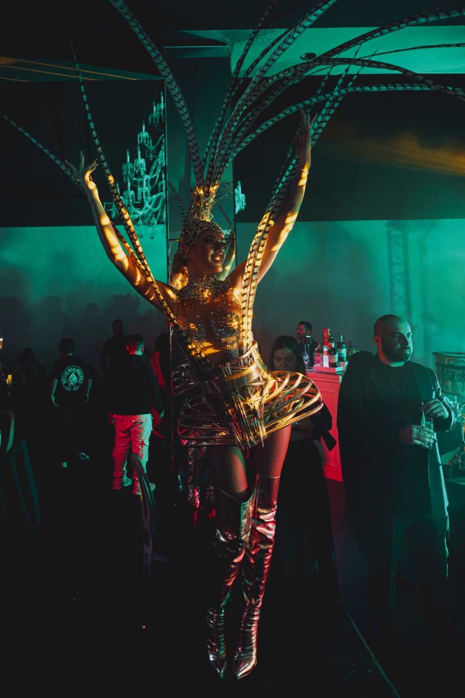 Performeuse en costume doré et coiffe rayonnante au milieu des invités, Drop Music