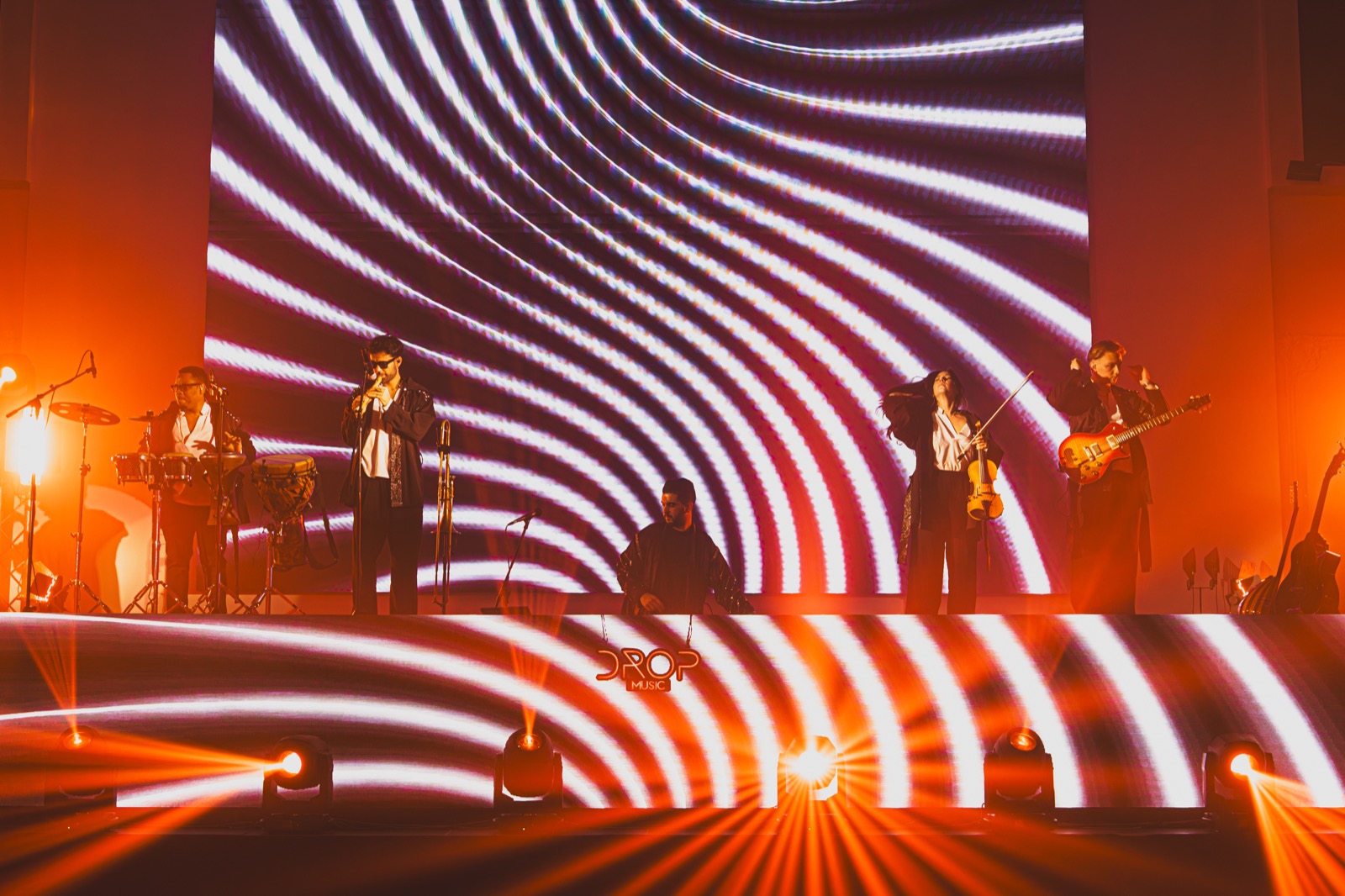 Violon et claviers en contre-jour devant un écran LED à motifs, DJ Live Drop Music
