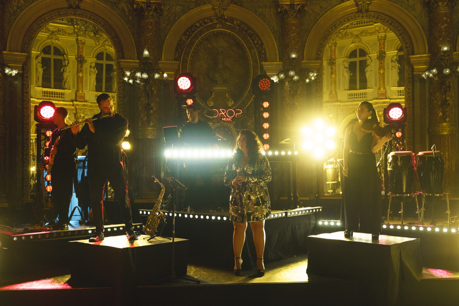 Chanteuse et musiciens sur deux praticables dans une salle à colonnes, DJ Live Drop Music
