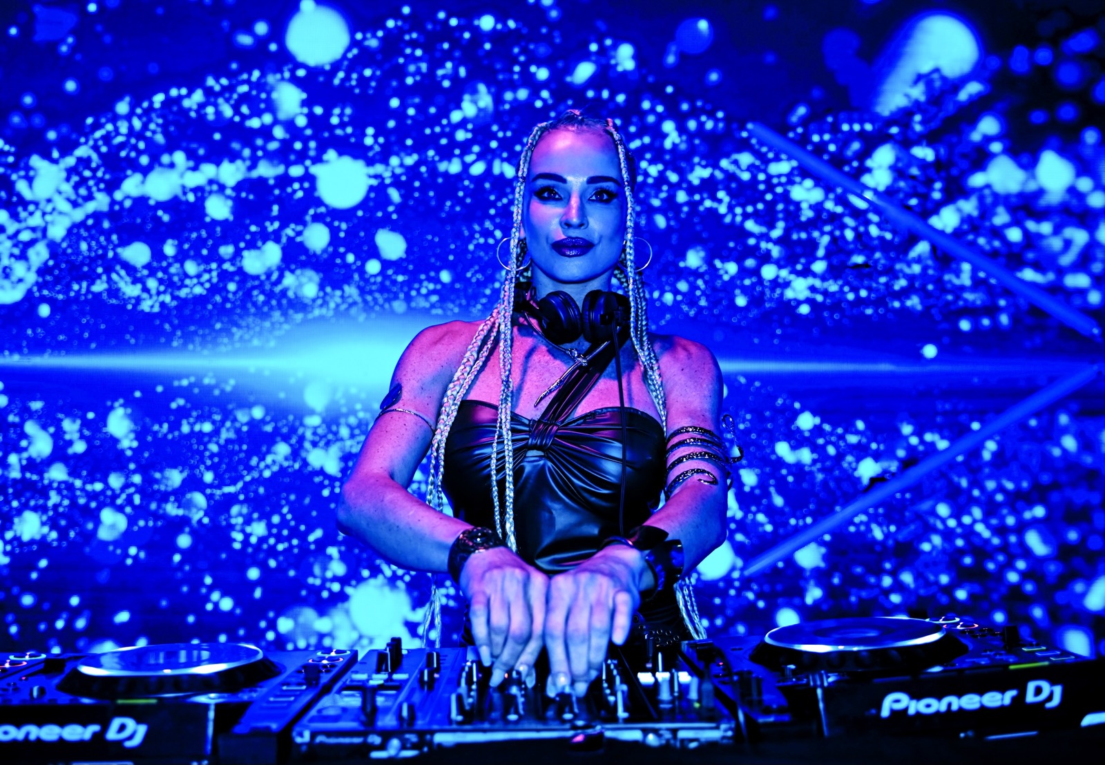 DJette aux platines devant un mur de paillettes bleu, Drop Music