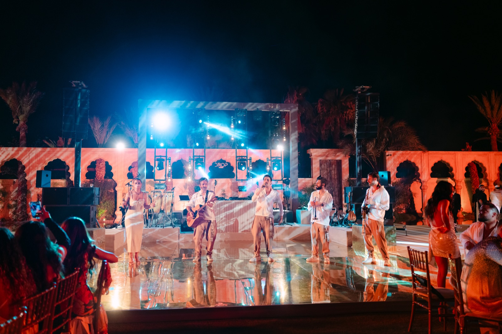 Scène en extérieur sous les arches, danseurs et musiciens live devant les invités, Drop Music