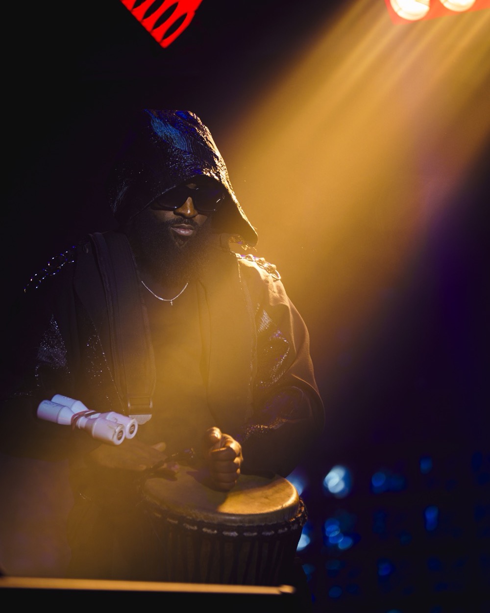 Percussionniste au djembé dans un faisceau de lumière doré, Drop Music