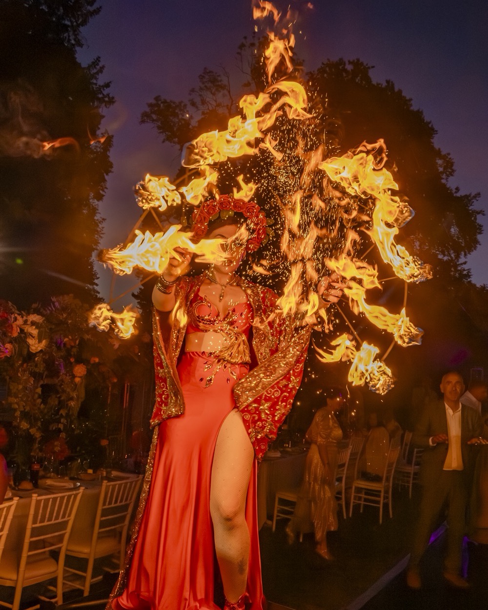 Performeuse en robe rouge et coiffe enflammée pendant une soirée en extérieur, Drop Music