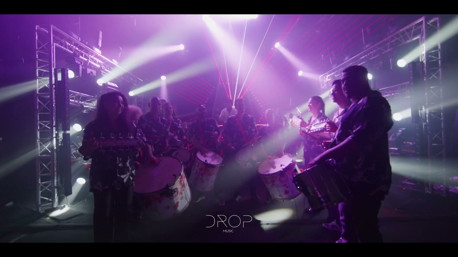 Percussionnistes et grosses caisses sur scène, en lumière violette, Drop Music